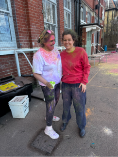 Two women standing smiling with coloured powered on them