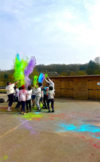 A group of children throwing green and purple powder into the air