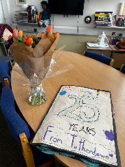 table with vase of flowers and card with 25 years written on cover