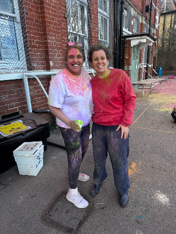 Two people standing next to each other covered in colourful powder
