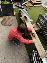 Child playing with toy cars on wooden plank