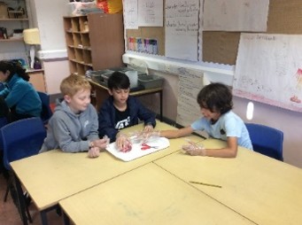three pupils around a table with sheep heart ready to dissect