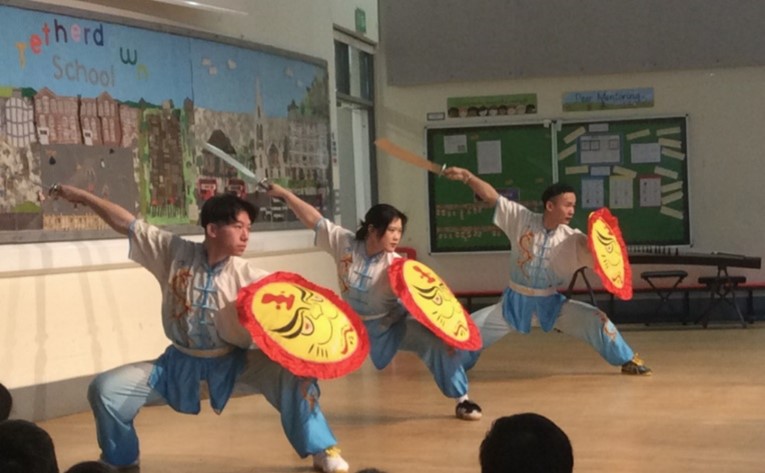Three people crouched with shields in martial arts display