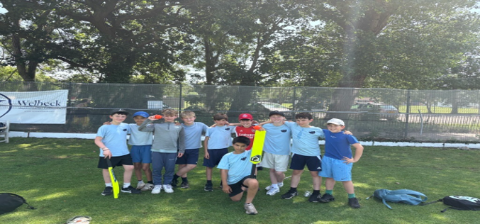 Y5&6 pupils in a line with two yellow cricket bats for a photo