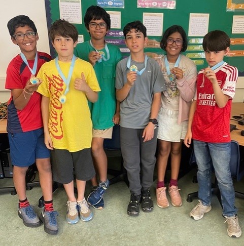 Six pupils in a line with chess medals around their necks