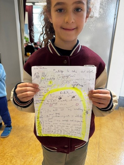Girl holding sheet of paper with writing on up