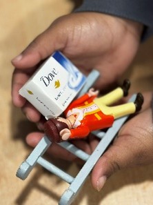 Child's hand holding small toy: lego figure and dove soap